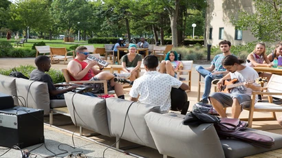 students play instruments on the patio outside Williams Center as students look on